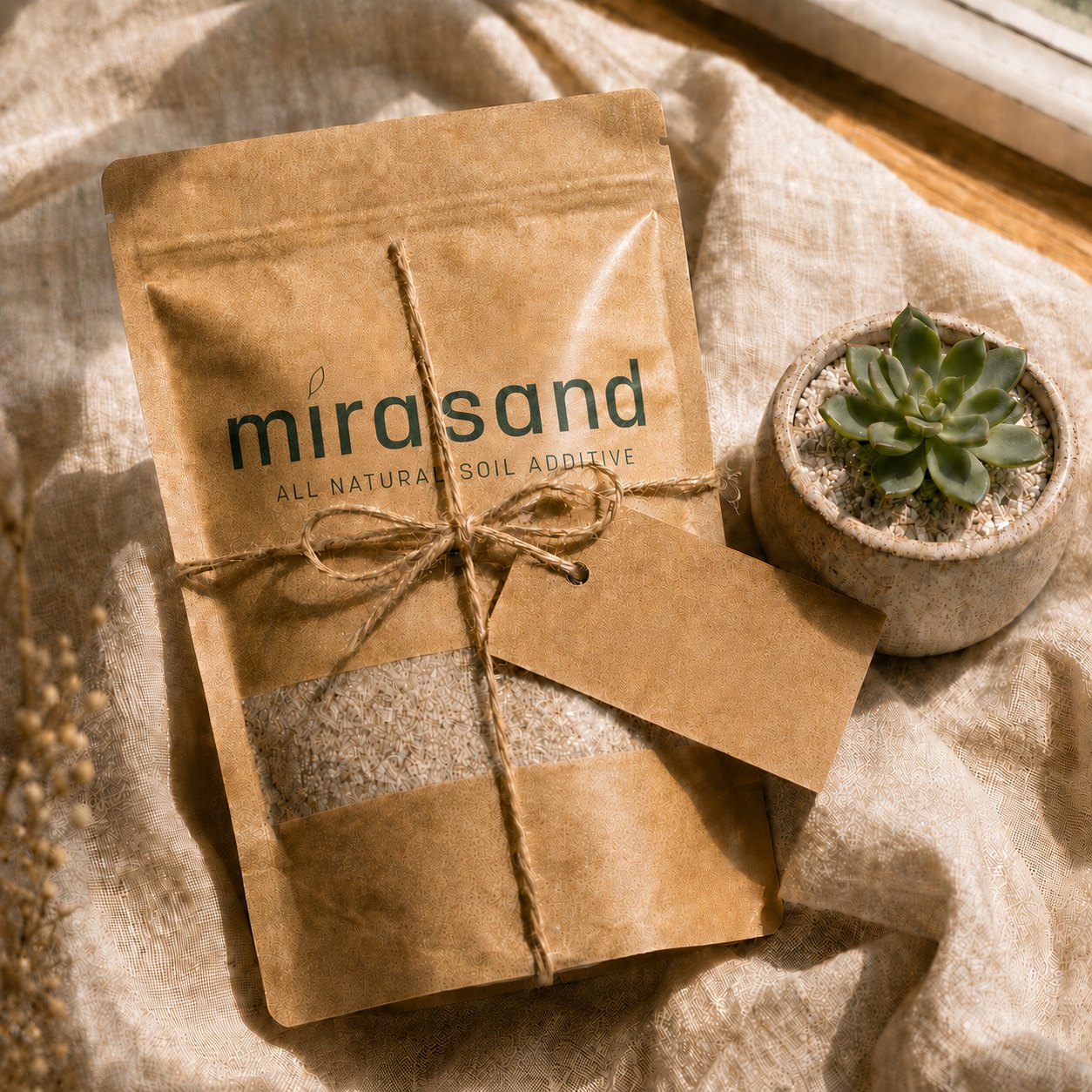 Mirasand pouch tied with twine and a blank kraft gift tag beside a small succulent